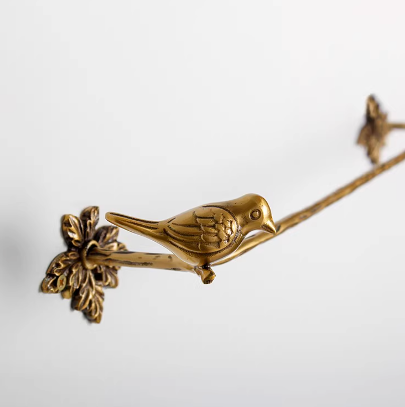 Gold brass bird bathroom set towel rack and toilet paper holder on white background.